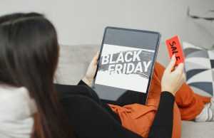Woman reading a Black Friday email on a tablet while lying on the couch